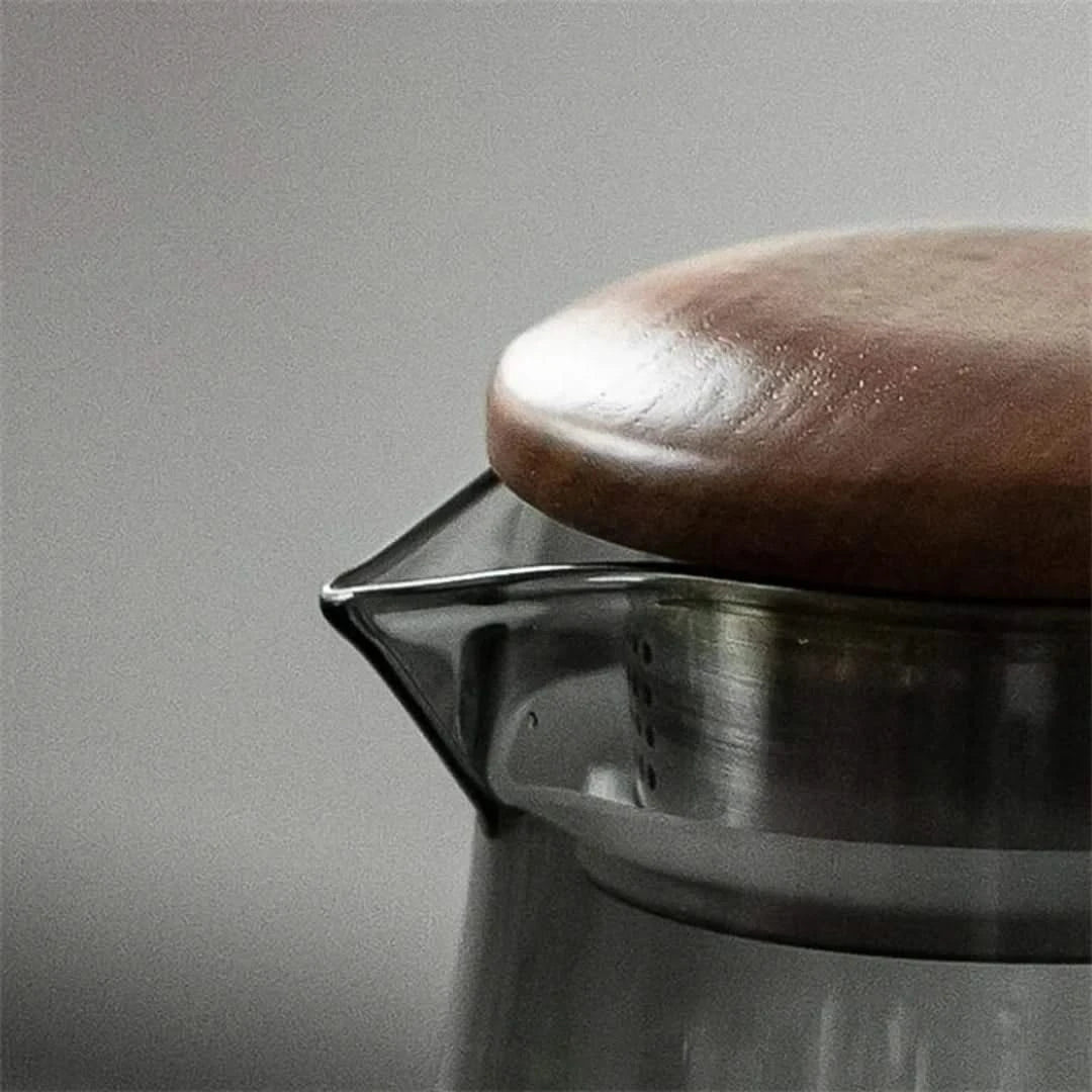 Josh & Tate - Montara Elegant Glass Pitcher - Close-up of a metal coffee filter with a brown coffee bean on a gray background