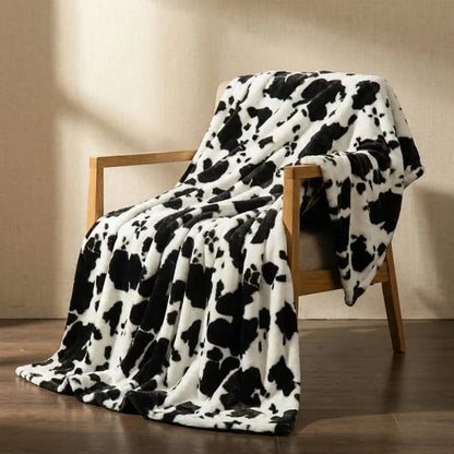 Josh & Tate MooWrap Cow Print Plush Blanket - black cow draped over armchair