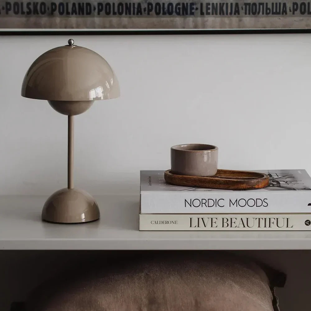 Beige table lamp on a surface with books and a small bowl in the background.