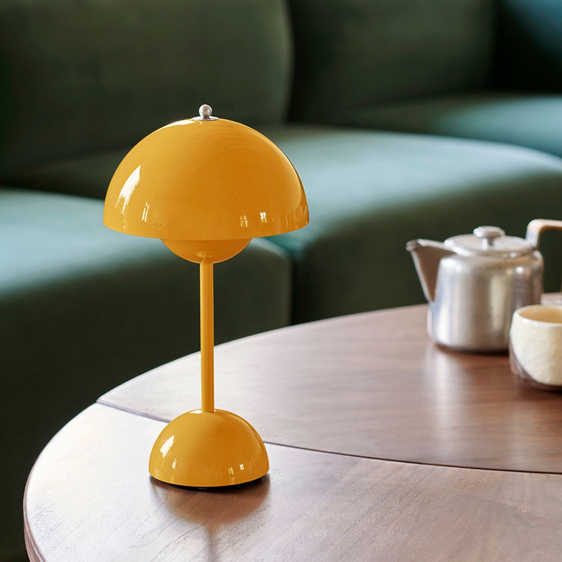 Yellow table lamp on a wooden table with a green sofa in the background