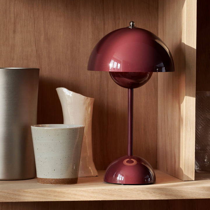 Maroon lamp on a wooden shelf with ceramic items