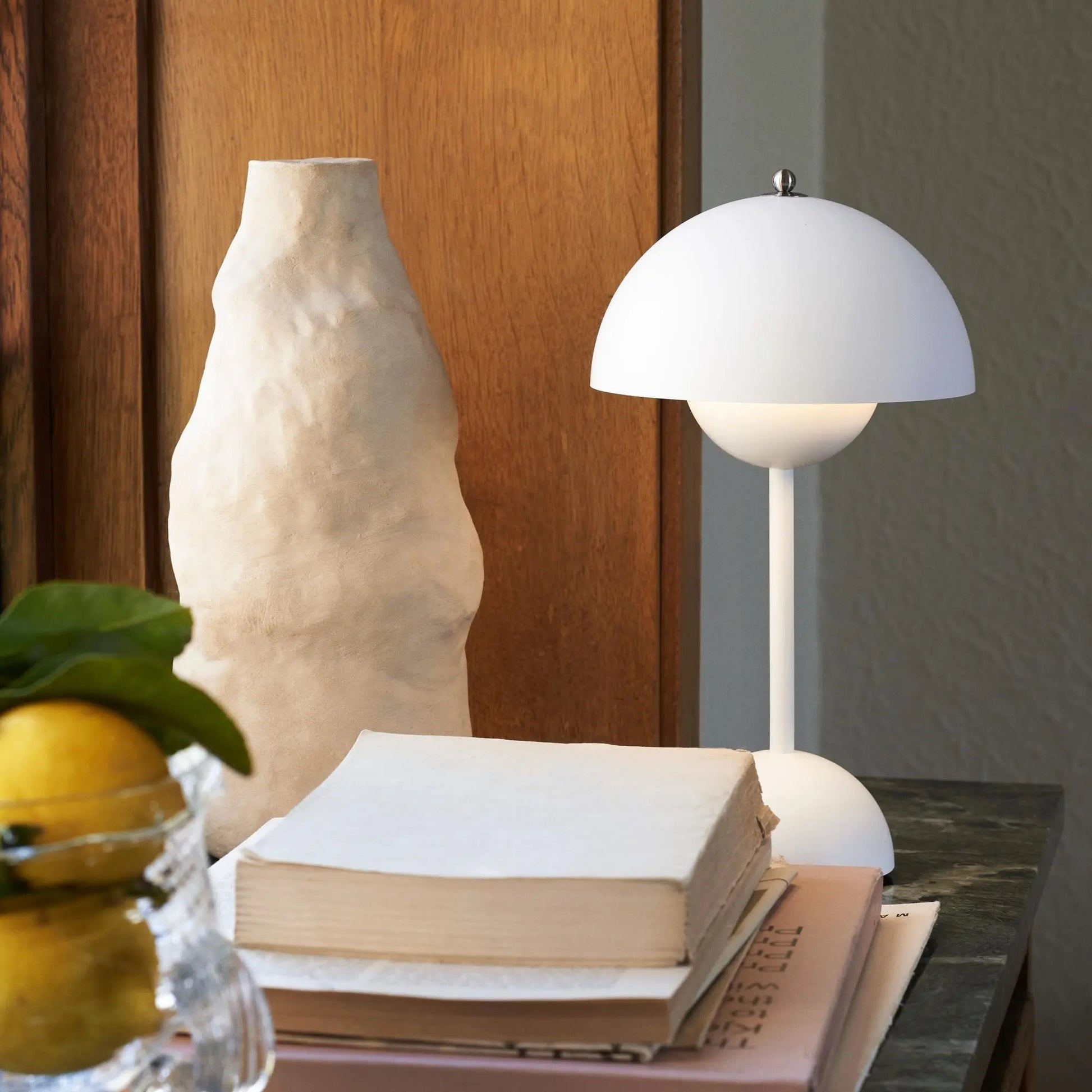 Decorative table setting with a lamp, books, and a vase on a wooden surface.