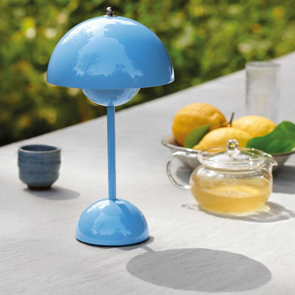 Blue table lamp on a white surface with a blurred outdoor background