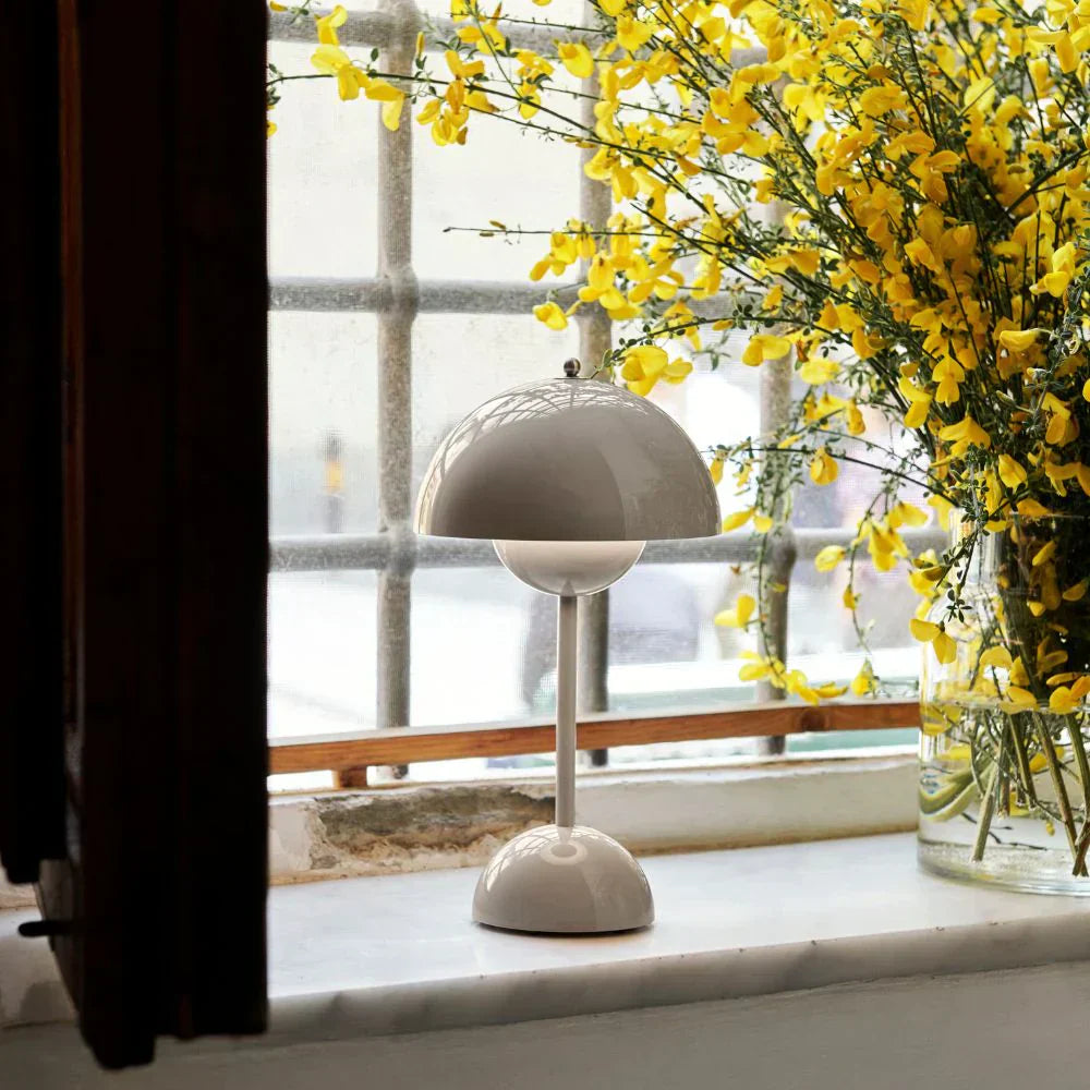 White lamp on a windowsill with yellow flowers in the background