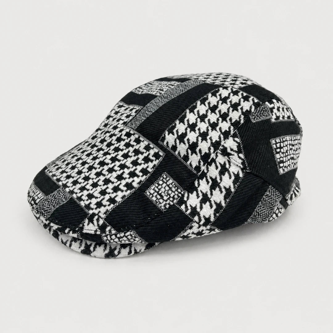 Josh & Tate - MosaicBrim™ Patchwork Flat Cap - A structured flat cap with a black and white patchwork design featuring houndstooth, checkered, and solid textured fabric panels, photographed on a light gray background.