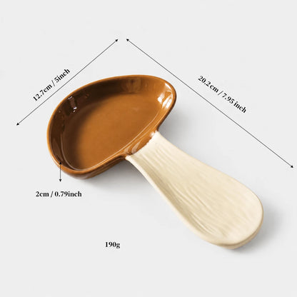 Josh & Tate - MushPerch™ Kitchen Spoon Holder - A ceramic mushroom-shaped spoon or scoop with a glossy brown cap and a textured off-white handle, shown on a light gray background with overlaid dimension lines and text indicating measurements and weight.