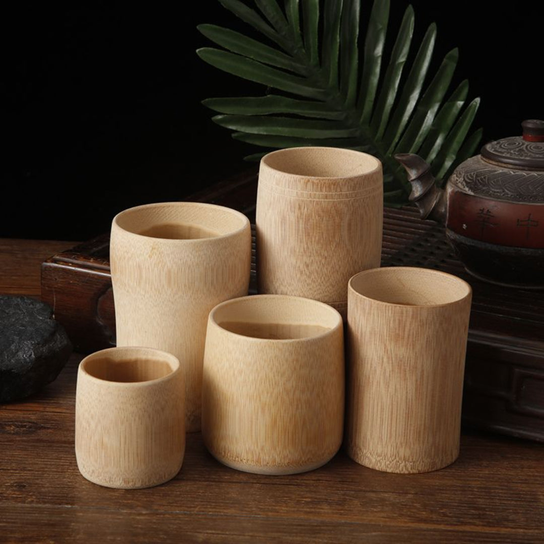 Set of wooden cups on a dark surface with a leafy background
