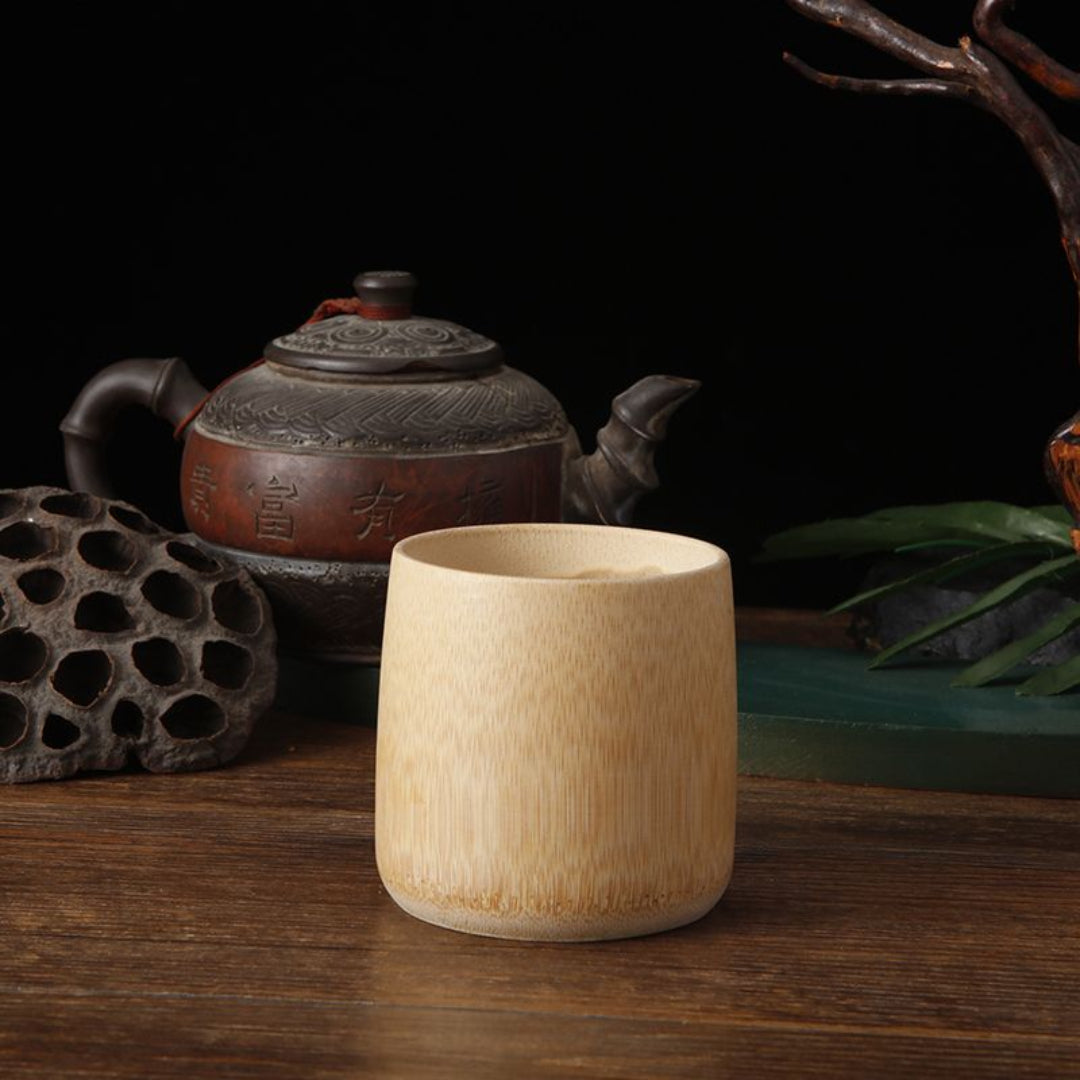 Wooden cup on a wooden surface with a teapot and decorative elements in the background