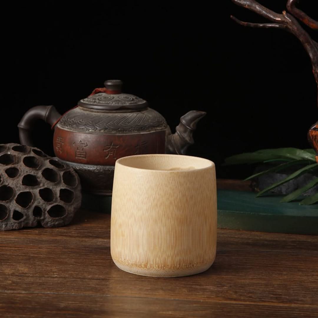 Wooden cup on a wooden surface with a teapot and decorative elements in the background
