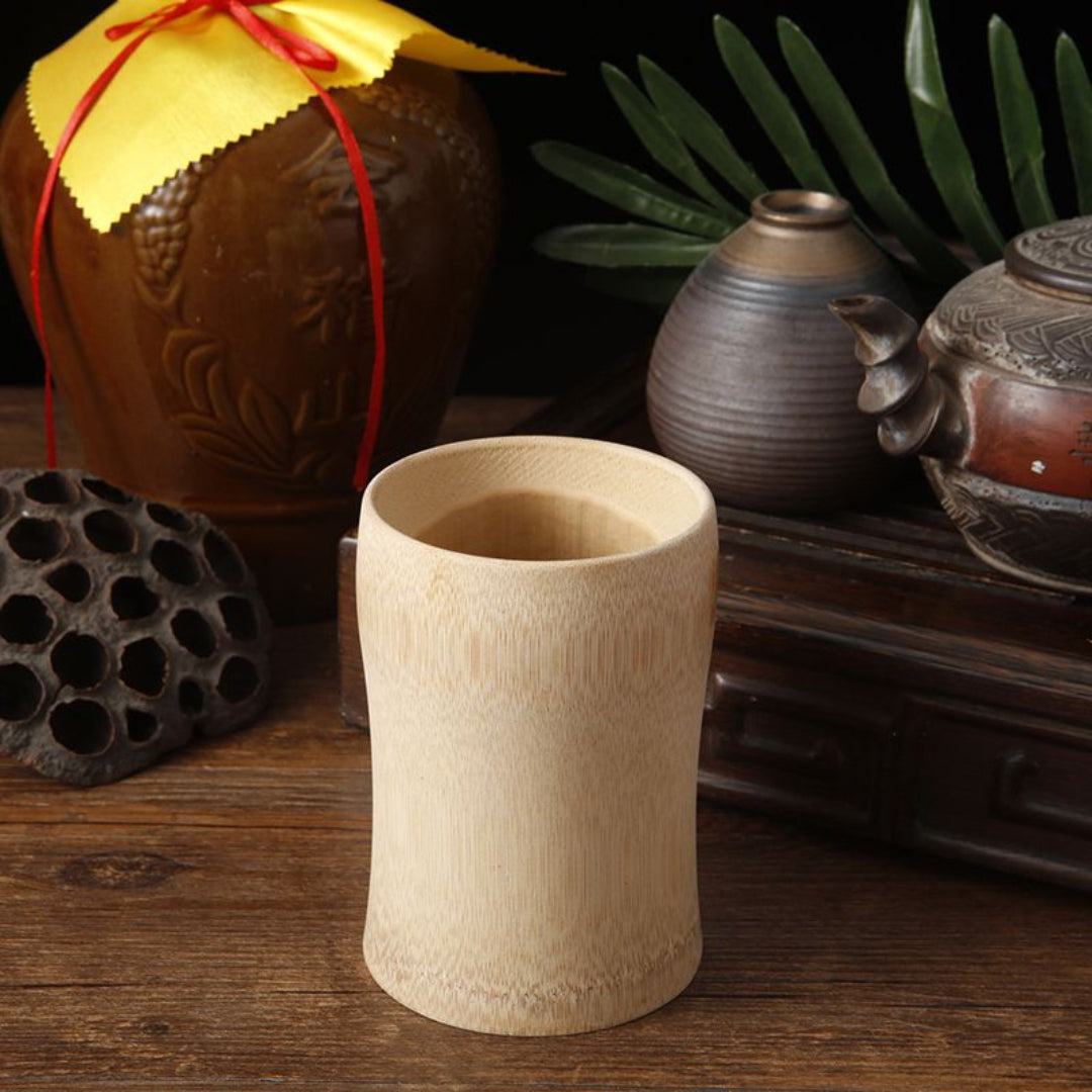 Beige ceramic cup on a wooden surface with traditional Chinese pottery in the background