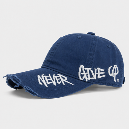 Josh & Tate - NeverGiveUp™ Baseball Cap - A navy blue distressed baseball cap with white embroidered text reading 'NEVER GIVE UP' across the brim and side panels, shown on a light gray background.
