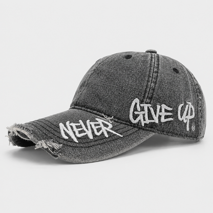 Josh & Tate - NeverGiveUp™ Baseball Cap - A distressed black washed denim baseball cap featuring white embroidered text reading 'NEVER' on the brim and 'GIVE UP' on the side, set against a light gray background.