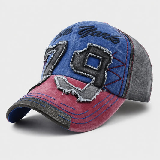 A distressed denim baseball cap with a blue front panel, pink brim, and gray side panels, featuring large '79' patchwork embroidery and 'New York' script.
