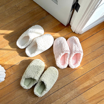 Pair of white fluffy slippers on a wooden floor.