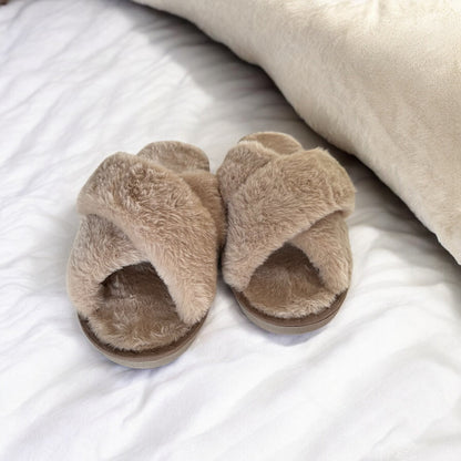 Pair of fluffy brown slippers on a white bed