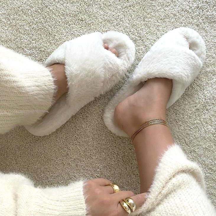 White fluffy slippers worn on a carpeted floor