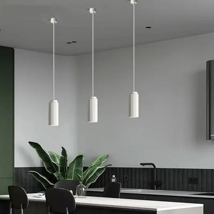 Modern kitchen interior with pendant lights, a plant, and a white countertop.