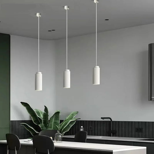 Modern kitchen interior with pendant lights, a plant, and a white countertop.