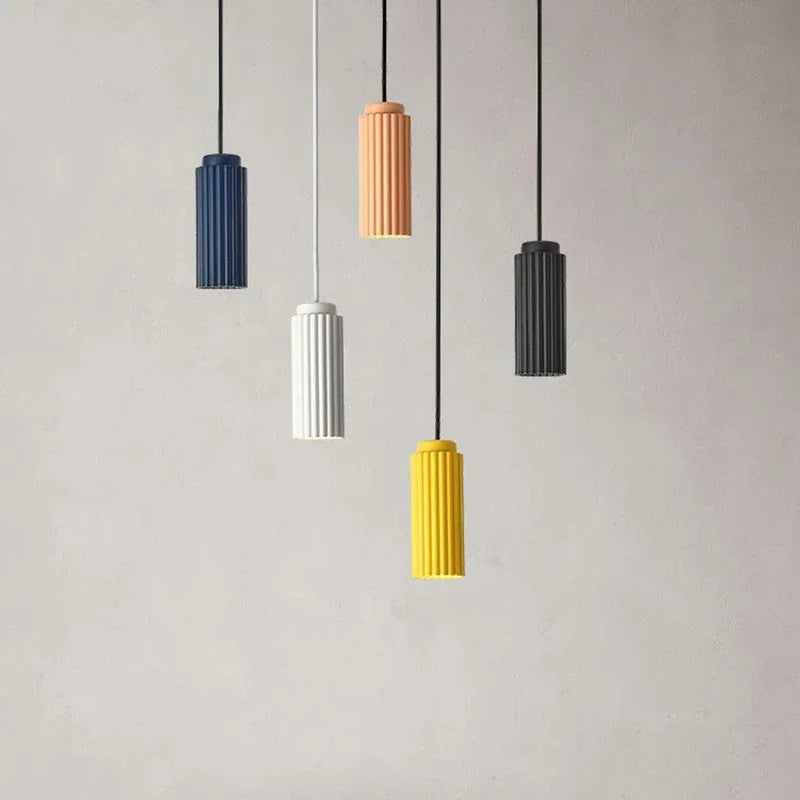 Five pendant lights in different colors hanging against a plain background