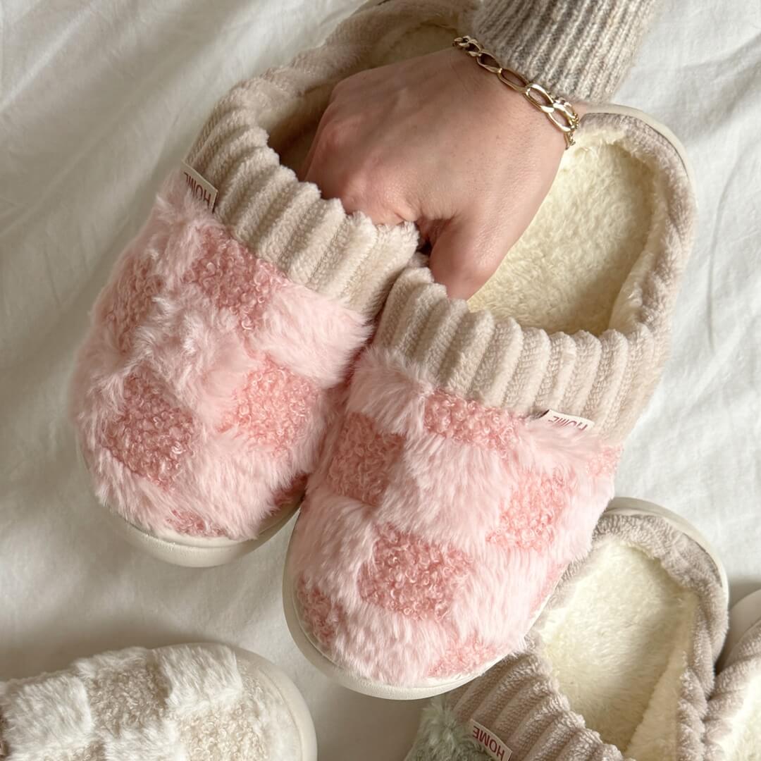 Pair of pink and white checkered slippers with fluffy texture on a light background