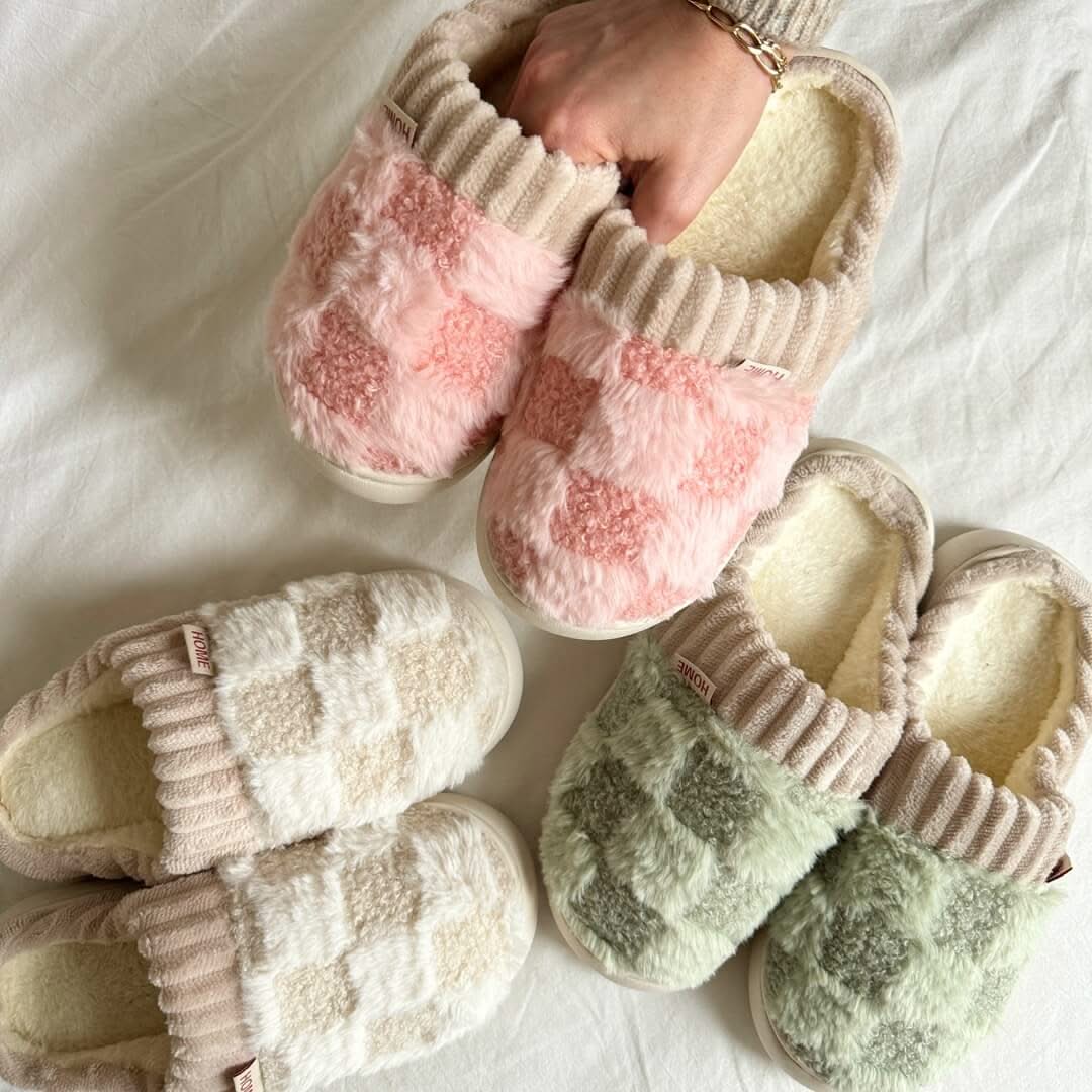 Pair of pink and green fuzzy slippers on a white surface