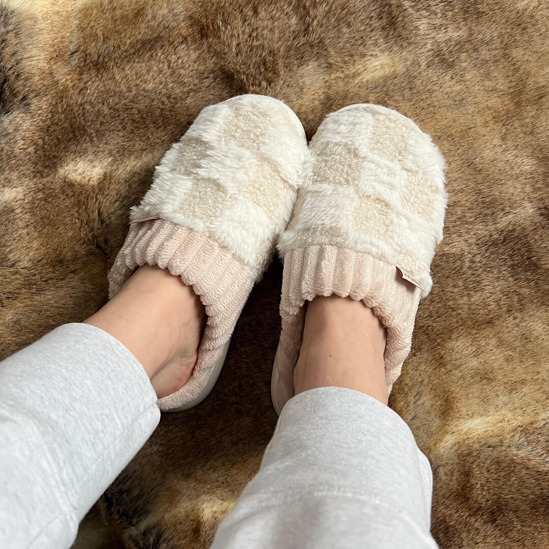 Beige slippers worn on a brown fur surface