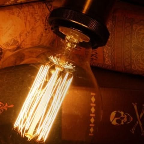 Vintage-style light bulb with intricate filaments on a textured surface