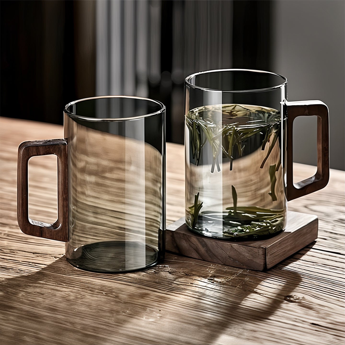 Two glass mugs with wooden handles on a wooden surface.