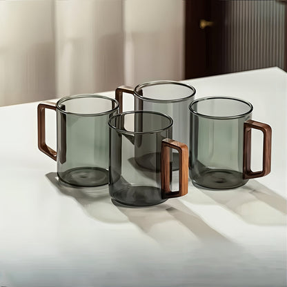 Set of four glass mugs with wooden handles on a white surface.