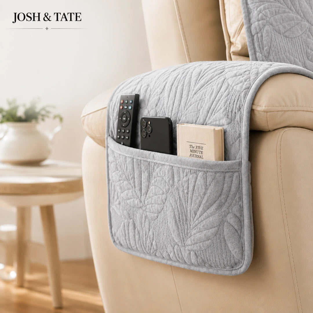 Josh & Tate - PalmSoft™ Quilted Chair Cover - Gray quilted sofa caddy with remote control, phone, and book on a beige sofa, with 'Josh & Tate' branding.