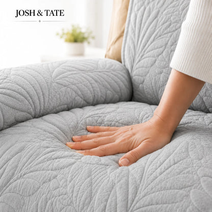 Josh & Tate - PalmSoft™ Quilted Chair Cover - Gray quilted cover on a sofa with a hand touching it, brand 'JOSH & TATE' visible.