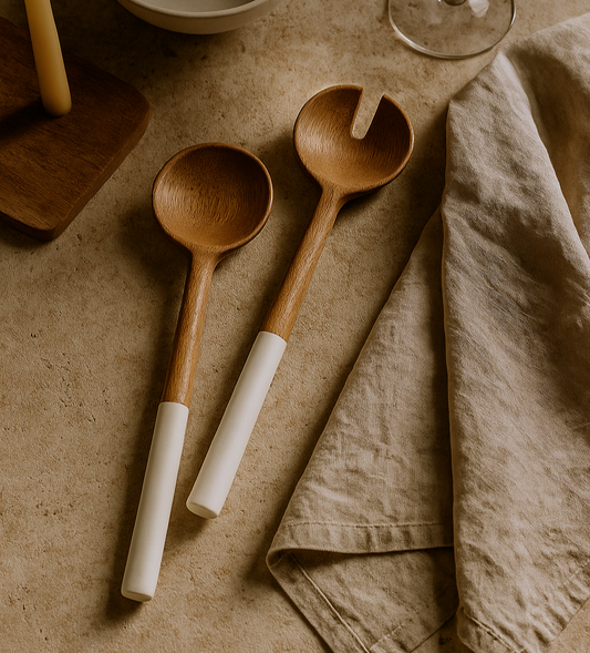 Two wooden spoons with white handles on a textured surface with a cloth.
