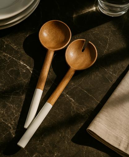 Two wooden spoons with white handles on a dark marble surface.