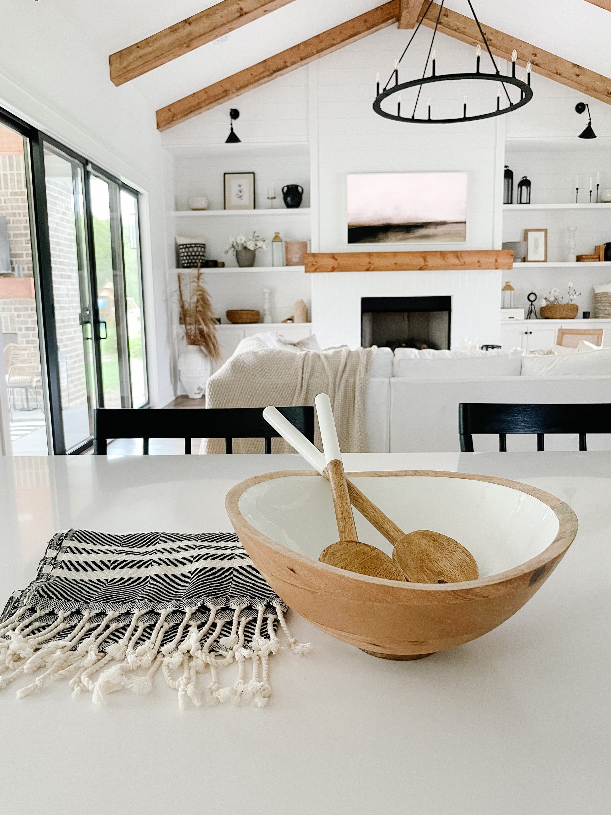 Wooden bowl with a wooden spoon on a white surface in a modern living room.