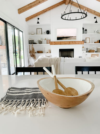 Wooden bowl with a wooden spoon on a white surface in a modern living room.