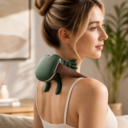 Josh & Tate - PawSoothe™ Shoulders and Neck Massager - A woman with her hair in a bun uses a green turtle-shaped neck and shoulder massager on the back of her neck in a softly lit indoor setting.