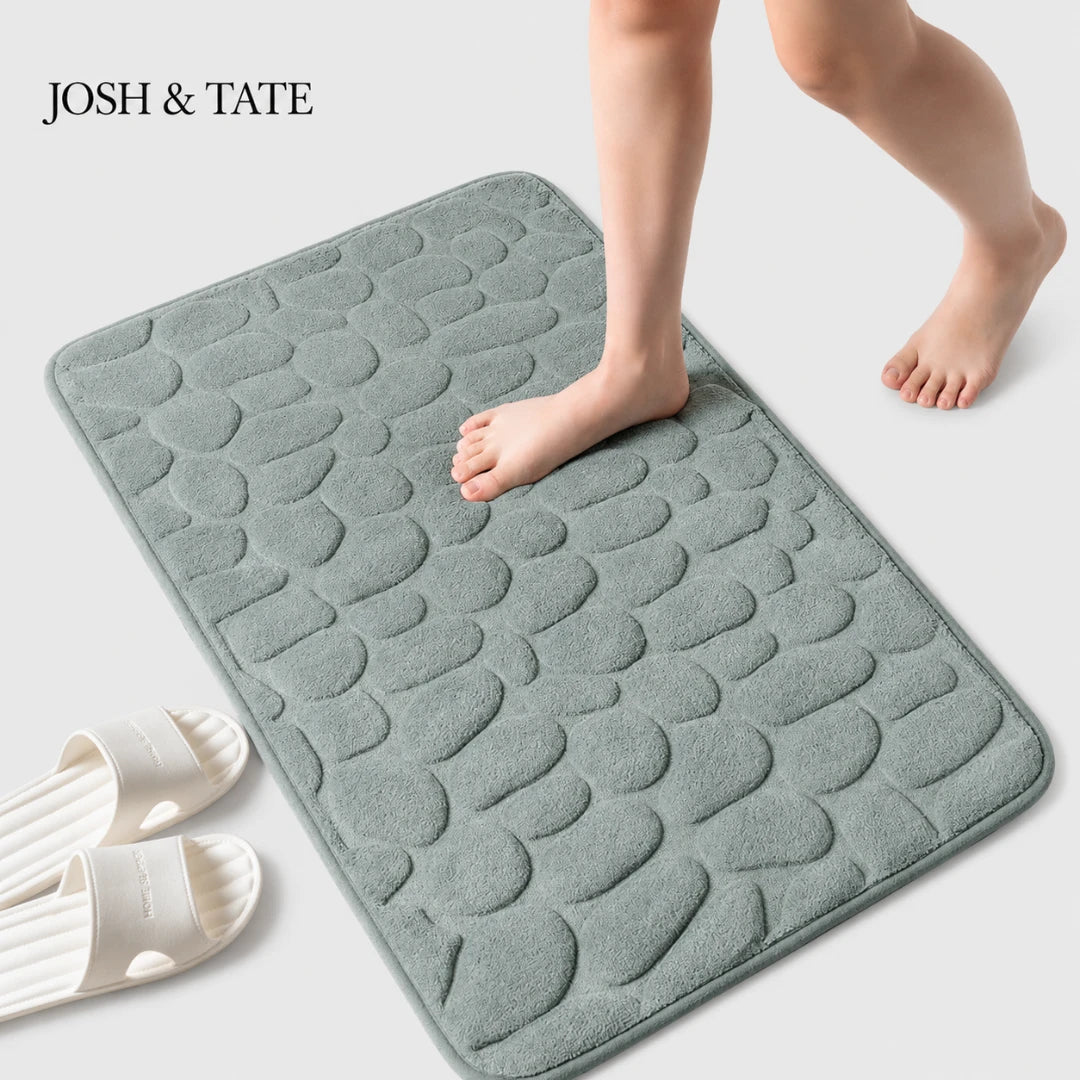 Josh & Tate - PebbleSoft™ Non-Slip Memory Foam Mat - Gray textured bath mat with a child's feet stepping onto it, on a light gray background.