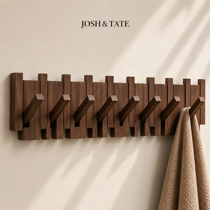 Josh & Tate - PianoHook™ Solid Wood Wall Rack - Wooden wall-mounted coat rack with multiple hooks on a beige wall, featuring the brand 'Josh & Tate'.