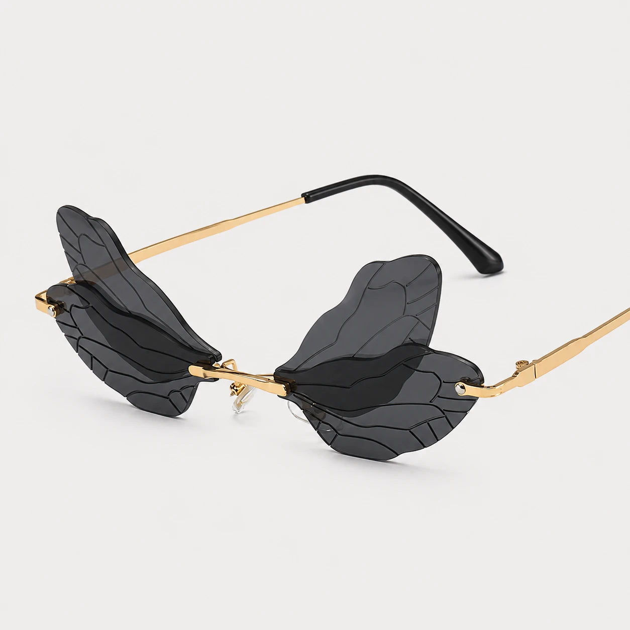Josh & Tate - PixieFrame™ Butterfly Sunglasses - Winged sunglasses with black translucent lenses shaped like stylized wings, gold metal arms, and black temple tips, shown on a light gray background.