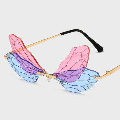 Josh & Tate - PixieFrame™ Butterfly Sunglasses - Unusual rimless sunglasses with translucent wing-shaped lenses in pink, purple, and blue, supported by thin gold metal arms with black temple tips, shown on a light gray background.