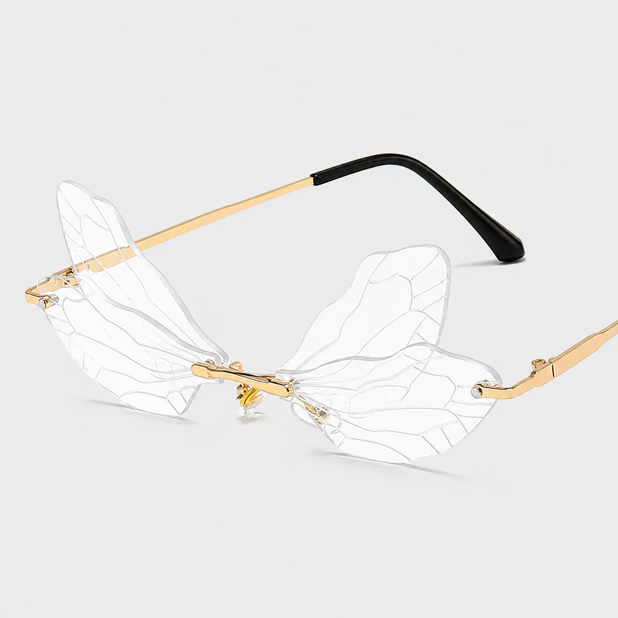 Josh & Tate - PixieFrame™ Butterfly Sunglasses - Rimless butterfly-style eyeglasses with clear patterned wings and gold metal temples, shown on a light gray background.