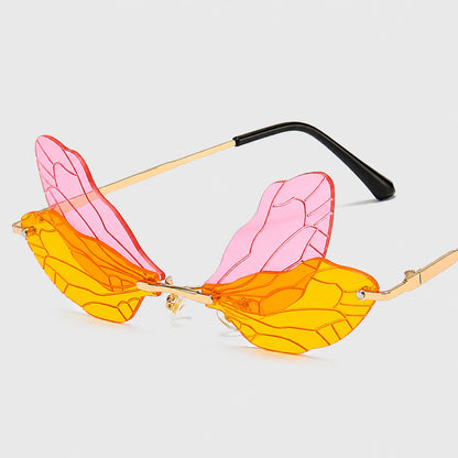 Josh & Tate - PixieFrame™ Butterfly Sunglasses - Wing-shaped sunglasses with translucent pink and orange lenses, gold metal frames, and black temple tips, shown on a light gray background.