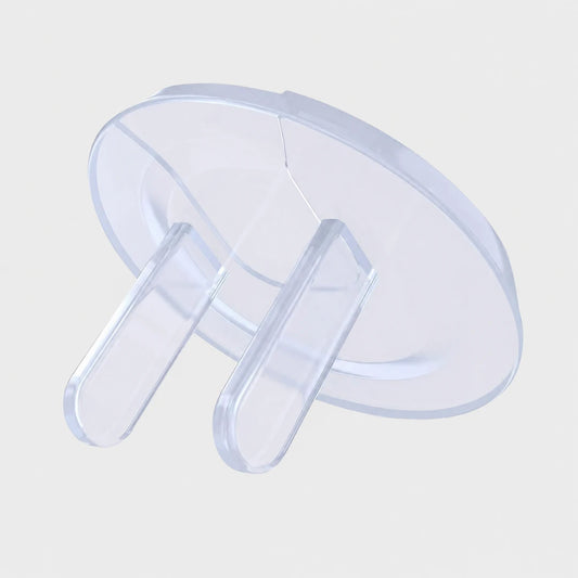 Josh & Tate - PlugLock™ Outlet Covers - A clear plastic baby safety guard or door stopper with a circular base and two vertical prongs, shown on a light gray background.