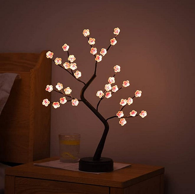 Decorative LED tree with cherry blossom lights on a wooden surface.