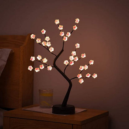 Decorative LED tree with cherry blossom lights on a wooden surface.