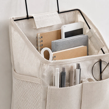 Josh & Tate - PocketPerch™ Hanging Organizer - A beige fabric desk organizer hanger with mesh pockets and a top compartment, shown holding notebooks, pens, a phone, and glasses against a light neutral background.