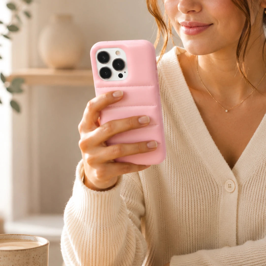 Woman holding a pink phone case with a blurred indoor background