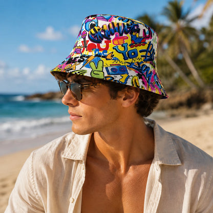 Josh & Tate - PrintedBucket™ Graffiti  Hat - A man wearing a colorful graffiti-print bucket hat and sunglasses, standing on a sandy beach with the ocean and palm trees in the background.