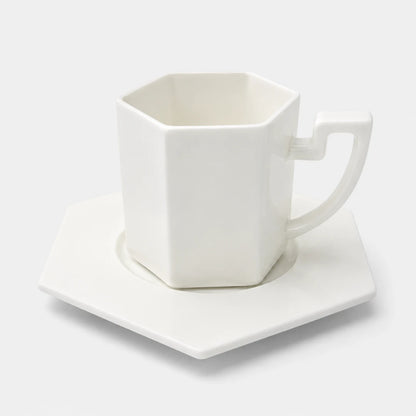 Josh & Tate - PrismCup™ Hexagon Cup & Saucer - A white hexagonal ceramic mug with a matching hexagonal saucer, photographed on a clean white background.