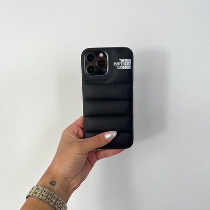 Hand holding a black phone case with 'The Puffer Case' branding on a white background